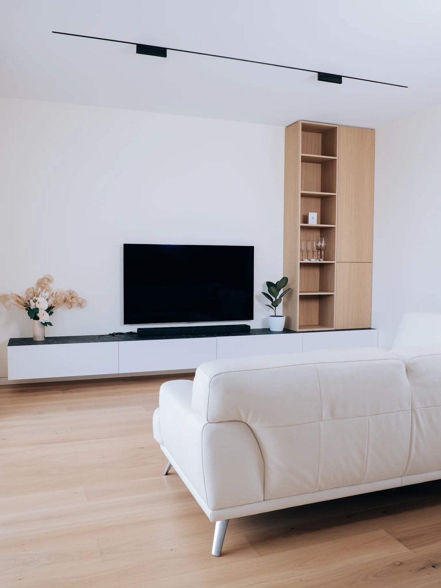 Modern living room with white sofa, TV stand, and bookshelf.