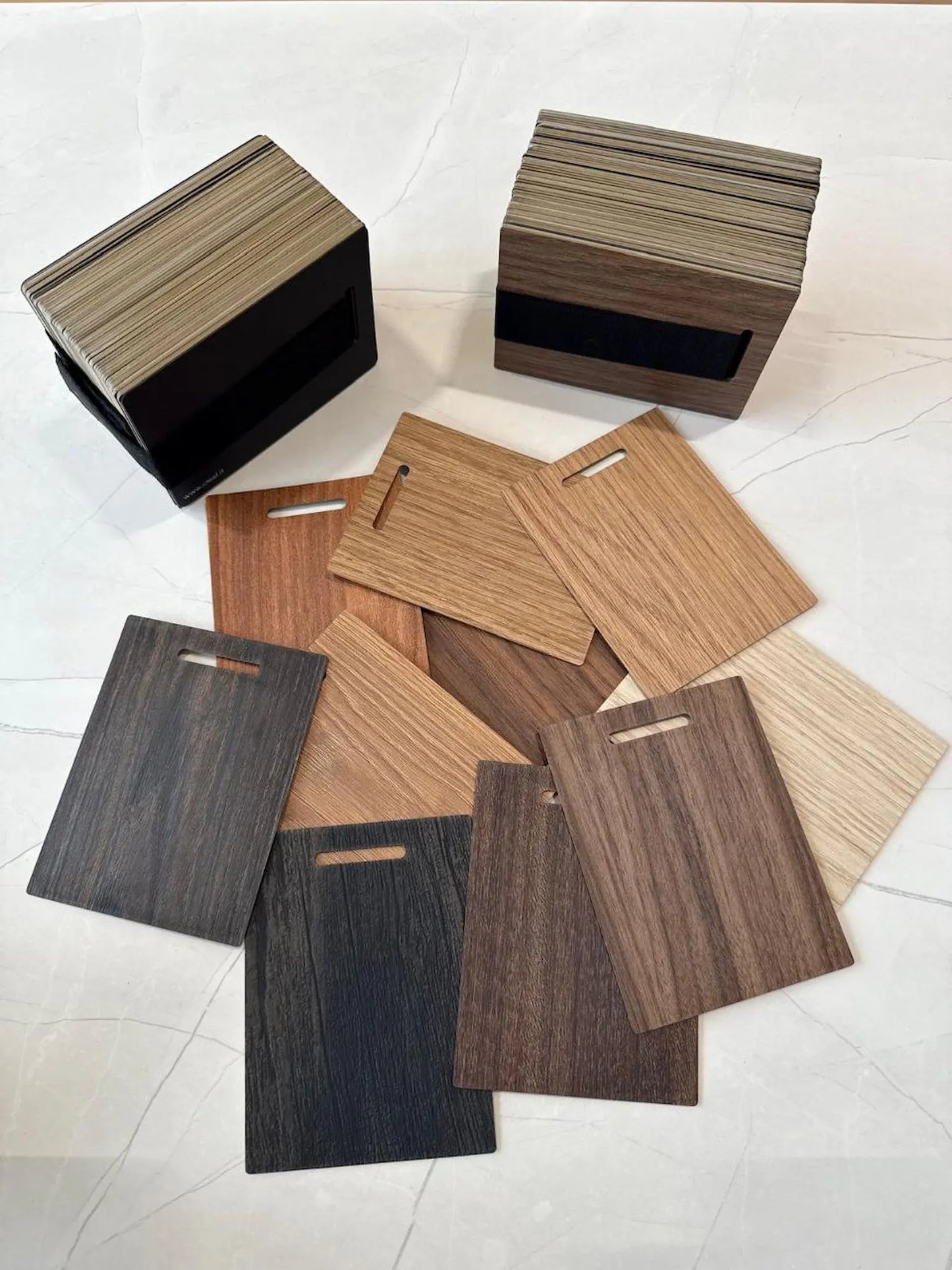 Collection of wooden cutting boards in various colors on a white floor.