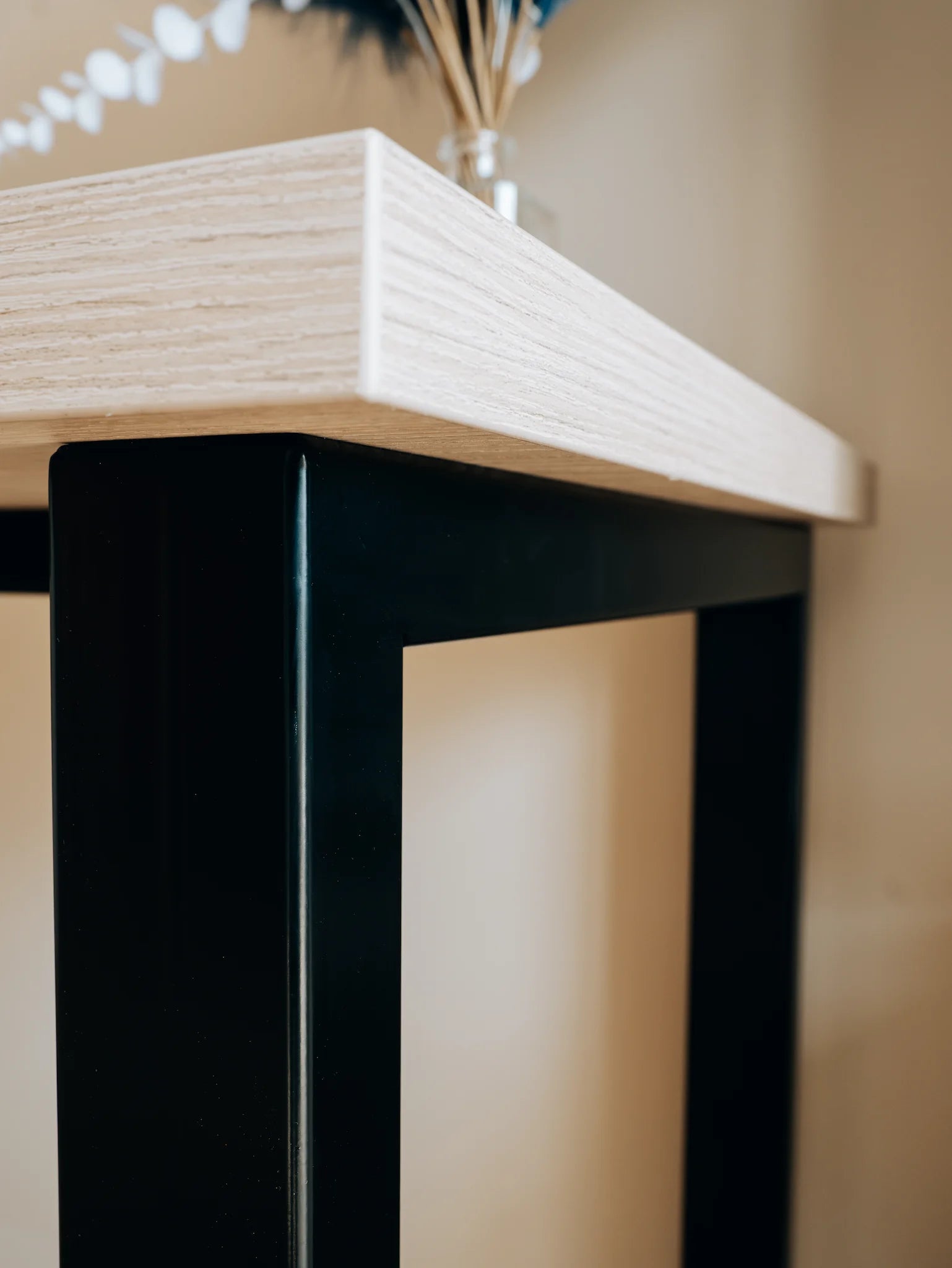 Close-up of a wooden table with black legs against a neutral background
