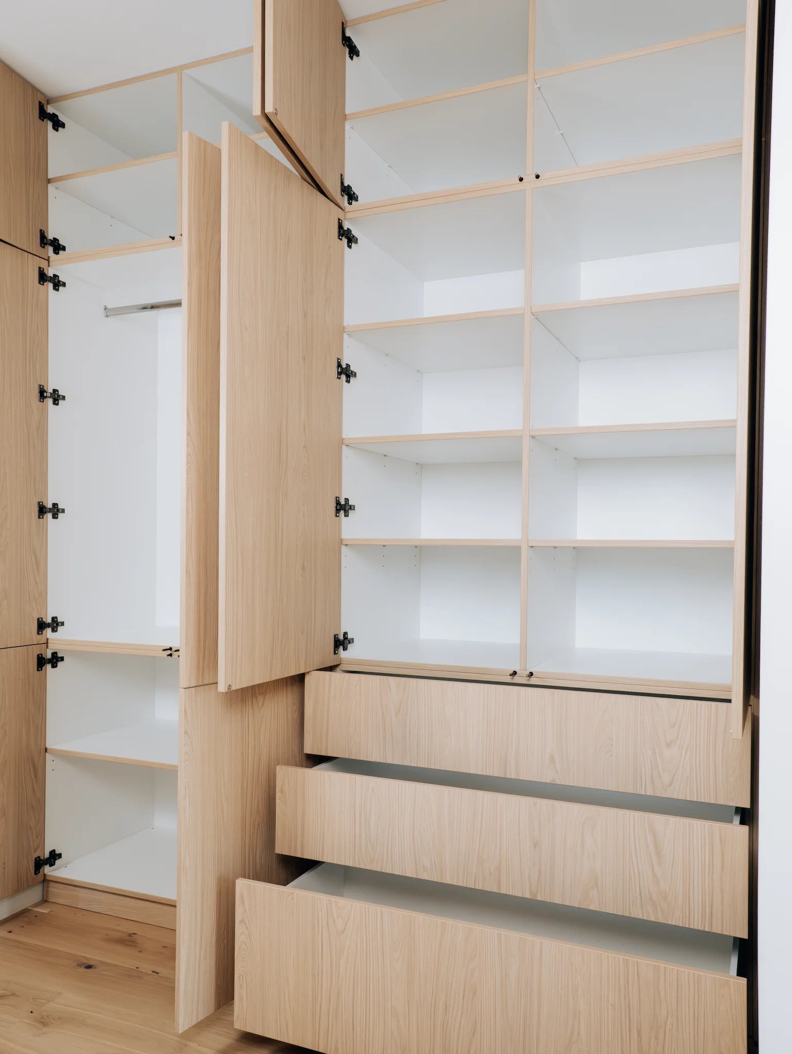 Wooden wardrobe with open doors and drawers in a room.