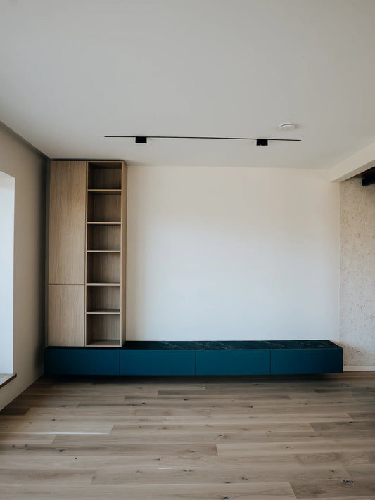 Modern interior with wooden bookshelf and blue entertainment console against a white wall.