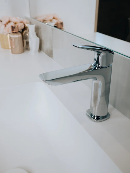Chrome faucet on a white sink with a blurred background
