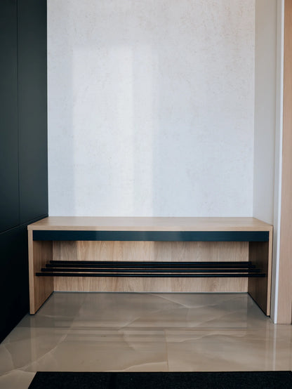 Wooden bench with black shelf against a white wall