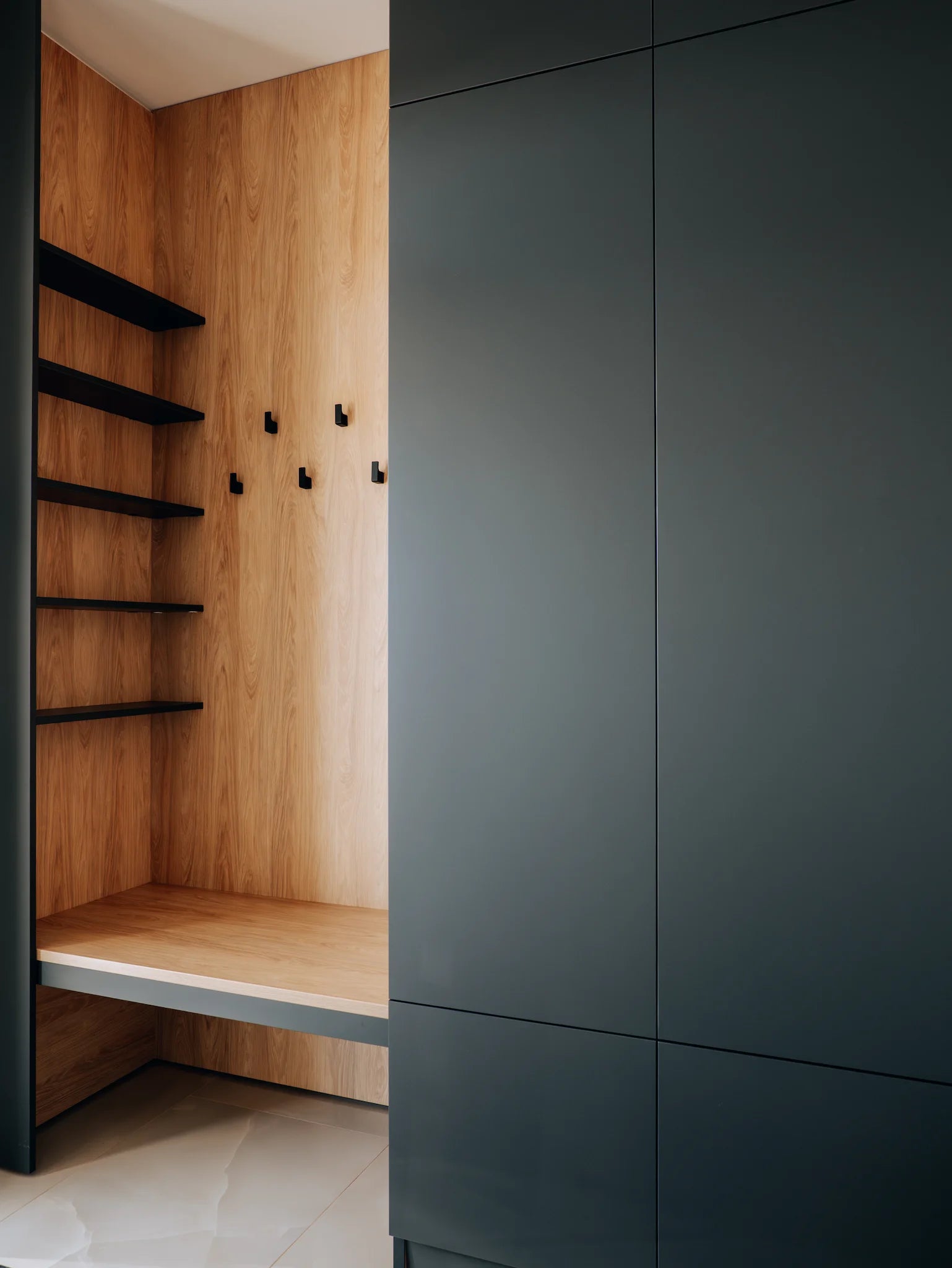 Modern interior with dark gray cabinets and wooden shelves.